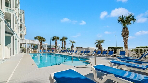 A pool area with blue lounge chairs and palm trees. - Grand Caribbean Pool Gym Beach View (Orange Beach)