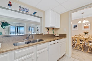 A kitchen with white cabinets, a granite countertop, and a dishwasher. - Gulf Tower 12A Direct Gulf-front 2 2 Sleeps 6 (Gulf Shores)