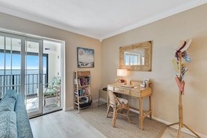 A room with a desk, chair, bookshelf, and a view through a sliding door to the outside. - Gulf Tower 12A Direct Gulf-front 2 2 Sleeps 6 (Gulf Shores)