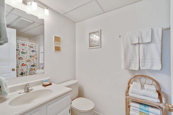 Une salle de bain avec un lavabo blanc, des toilettes, un miroir et un porte-serviettes.