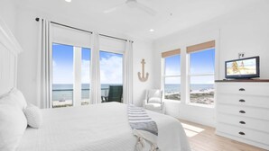 A bedroom with a large bed, a TV, a dresser, and a view of the beach. - Lil Tip Sea 8 BR Private Pool Elevator Beach (Gulf Shores)