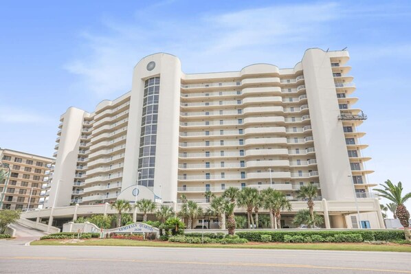 A multi-story hotel with a curved facade, balconies, and a central entrance. - Admirals Quarters 802 Amenities Galore Spacious (Orange Beach)
