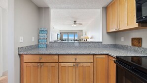 Een keuken met houten kastjes, een granieten aanrechtblad en een plafondventilator.