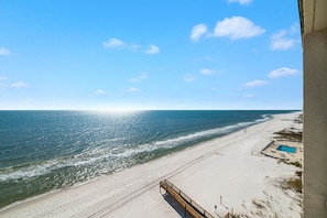 A beach with a wooden walkway leading to a pool area.