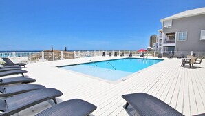 Ein Poolbereich mit Liegestühlen und einem Gebäude im Hintergrund.