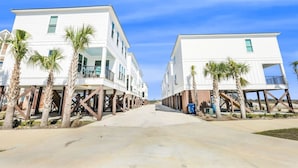 Ein Strandgrundstück mit zwei weißen Gebäuden, jedes mit einem Balkon und Palmen.