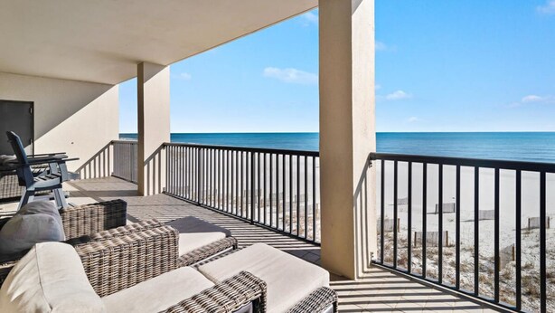 Een balkon met rieten meubilair en uitzicht op het strand.