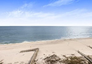 A beach with a wooden boardwalk leading to the water.