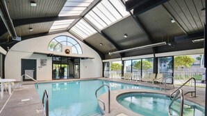 A large indoor swimming pool with a high ceiling and skylights, surrounded by lounge chairs and a small seating area. - Pelican Pointe1204 3BR 2BA Gulf-front (Orange Beach)