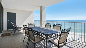 A balcony with a table and chairs, a door, and a view of the ocean. - Pelican Pointe1204 3BR 2BA Gulf-front (Orange Beach)