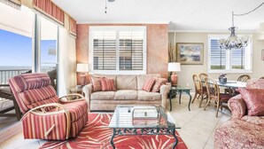 Ein Wohnzimmer mit einer Couch, Sesseln, einem Couchtisch und einem Essbereich mit Stühlen und einem Tisch.