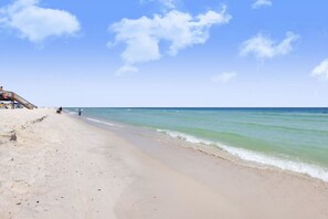 A beach with a wooden walkway leading to a building with a thatched roof. - Dear Time Beach House- Elevator Sleeps 10 Pool (Gulf Shores)