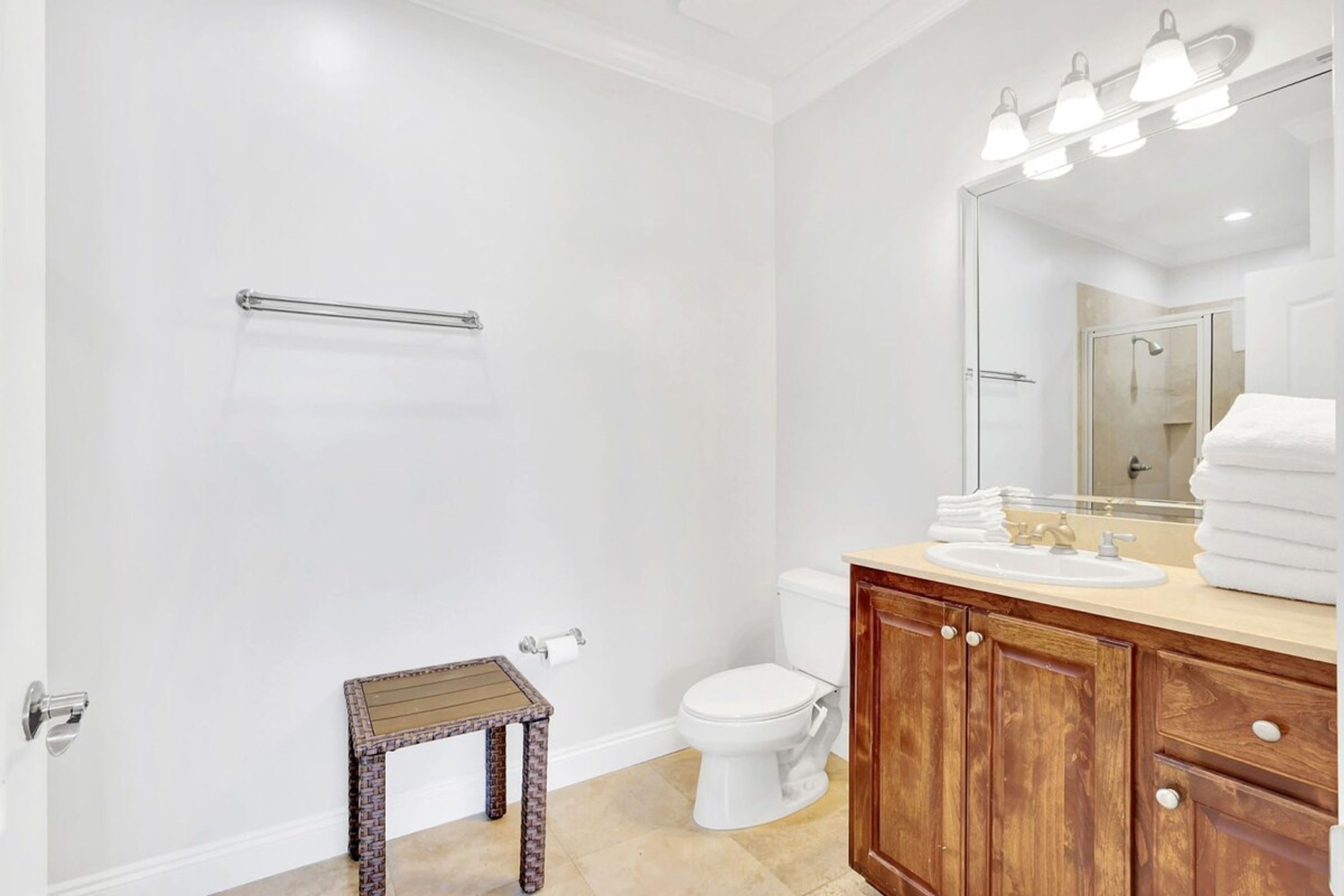 A bathroom with a toilet, sink, vanity, and a small table.