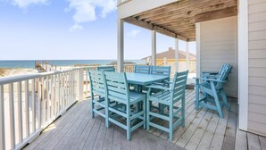 Une terrasse en bois avec une table et des chaises, donnant sur une plage.