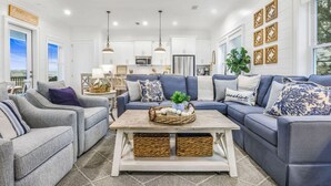 Ein geräumiges Wohnzimmer mit einer großen Eckcouch, einem Couchtisch und Blick auf die Küche im Hintergrund.