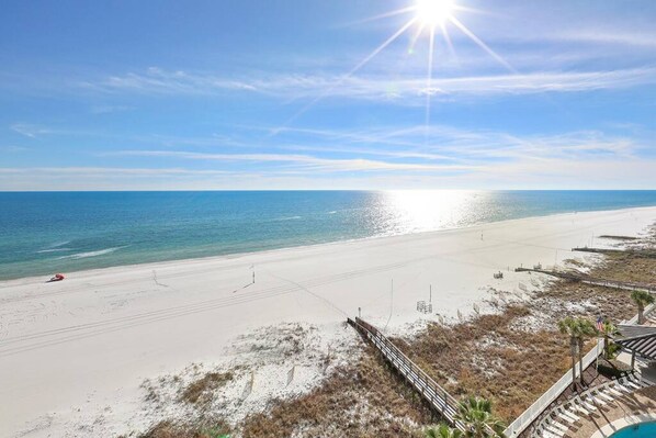 A beach with a wooden boardwalk leading to a pool area.