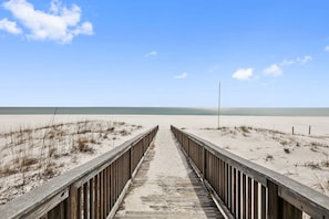 A wooden boardwalk leading to a beach with sand dunes and a clear blue sky. - Spanish Key 505 3 3 Next to the Flora-bama (Pensacola)