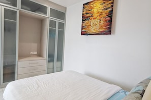 A bedroom with a bed, a wardrobe with glass doors, and a painting on the wall.