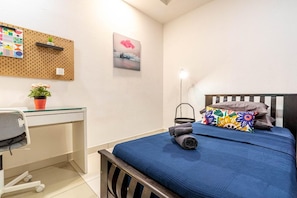 A bedroom with a bed, a desk, a chair, a wall-mounted pegboard, and a painting. - Urban Oasis Kuala Lumpur Apartment Sleeps 6 (Kuala Lumpur)
