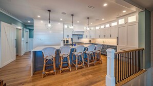 A modern kitchen with white cabinetry, a central island with bar stools, and pendant lighting.