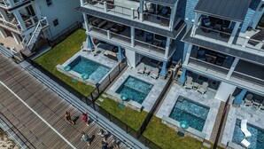 A multi-story building with a rooftop deck, multiple swimming pools, and outdoor seating areas.