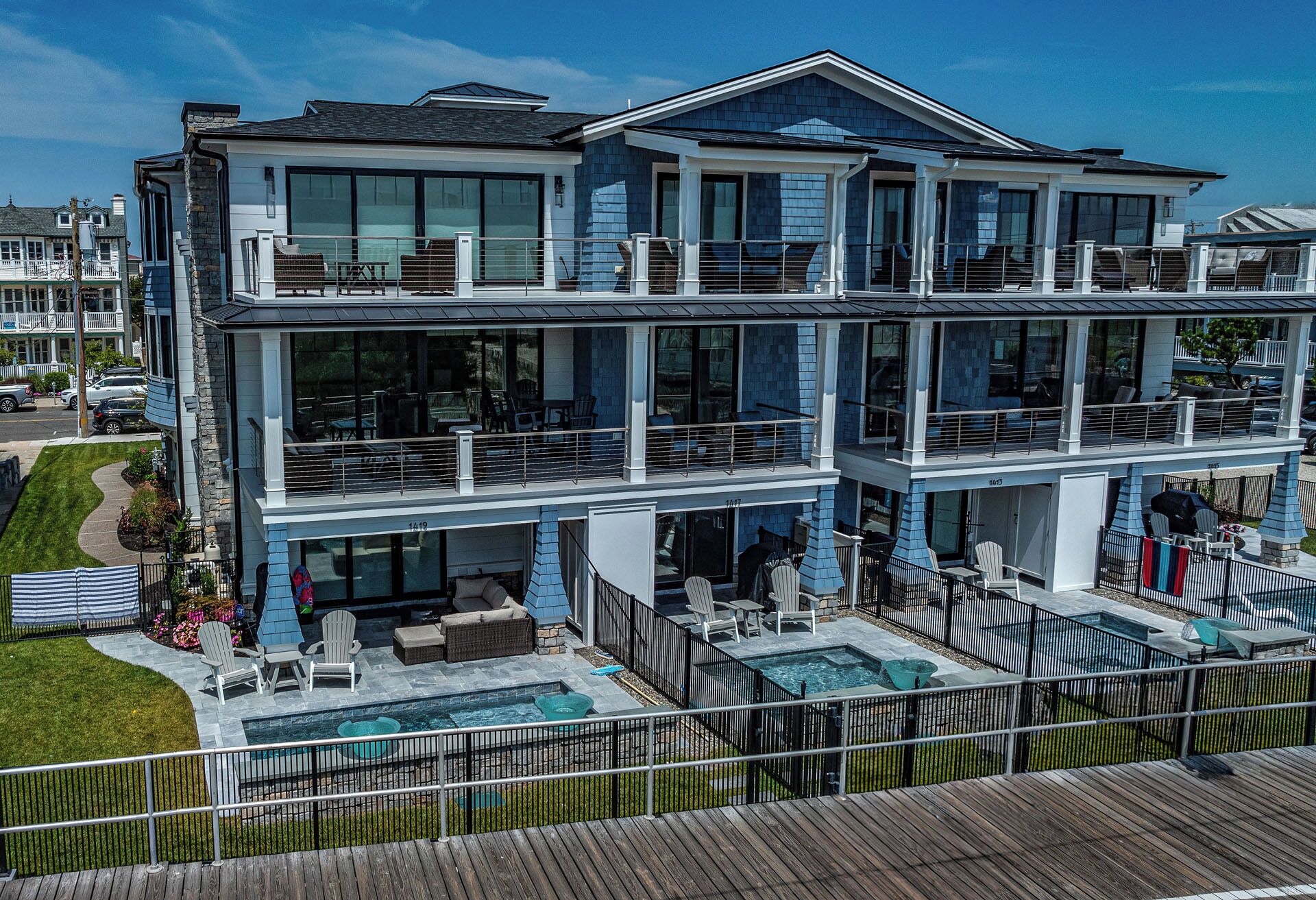 A multi-story house with a large balcony, outdoor seating, and a swimming pool.