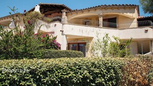 A two-story building with a balcony, surrounded by well-maintained hedges and flowering plants. - Villa Azzurra by Propertize - a few steps from the sea (Pittulongu)