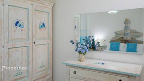 A bedroom with a dresser, a mirror, and a vase of flowers. - Villa Azzurra by Propertize - a few steps from the sea (Pittulongu)