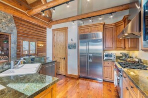 A kitchen with wooden cabinets, a stainless steel refrigerator, a built-in oven, and granite countertops.