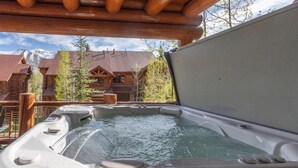 Ein Whirlpool mit Holzterrasse und Blick auf eine Berghütte.