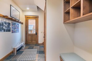 A hallway with a wooden door, a white radiator, a patterned rug, and a wall with framed pictures.