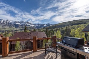 A deck with a grill and a view of mountains.