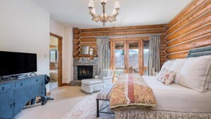 Ein rustikales Blockhaus-Interieur mit Fernseher, Kamin, Sofa und einer Chandelier.