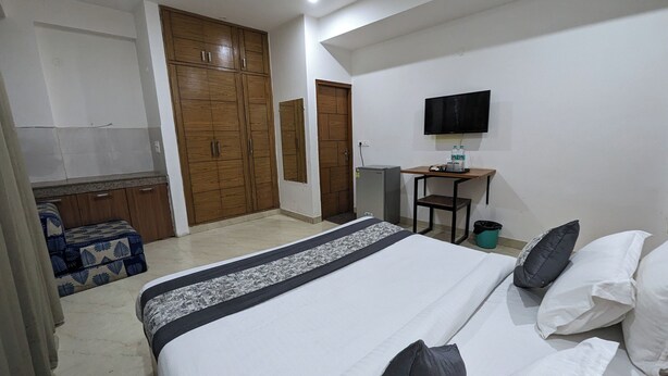 A bedroom with a bed, a desk with a chair, a television, and a wardrobe. - Hotel Prime Chhatarpur (New Delhi)