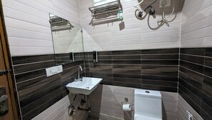 A bathroom with a sink, toilet, and towel rack. - Hotel Prime Chhatarpur (New Delhi)