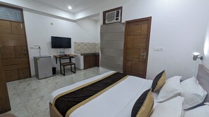 A bedroom with a bed, a desk, a television, and a wardrobe. - Hotel Prime Chhatarpur (New Delhi)