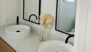 A bathroom with two white sinks, black faucets, and mirrors with black frames. - The Chic Beach Studio w/spacious patio

 (Newport Beach)