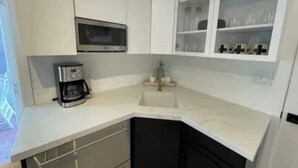 A kitchen with white cabinets, a microwave, a coffee maker, and a sink. - The Chic Beach Studio w/spacious patio

 (Newport Beach)
