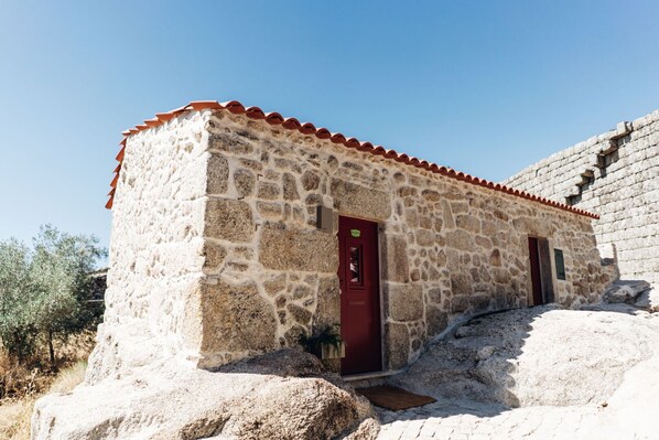 Un bâtiment en pierre avec une porte rouge et un petit porche.