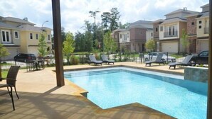 A swimming pool with lounge chairs and a covered patio area.