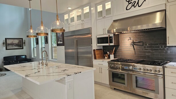 A modern kitchen with a central island, stainless steel appliances, and pendant lighting.