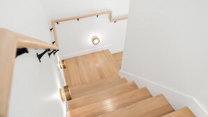 A wooden staircase with a handrail and a light fixture at the top.