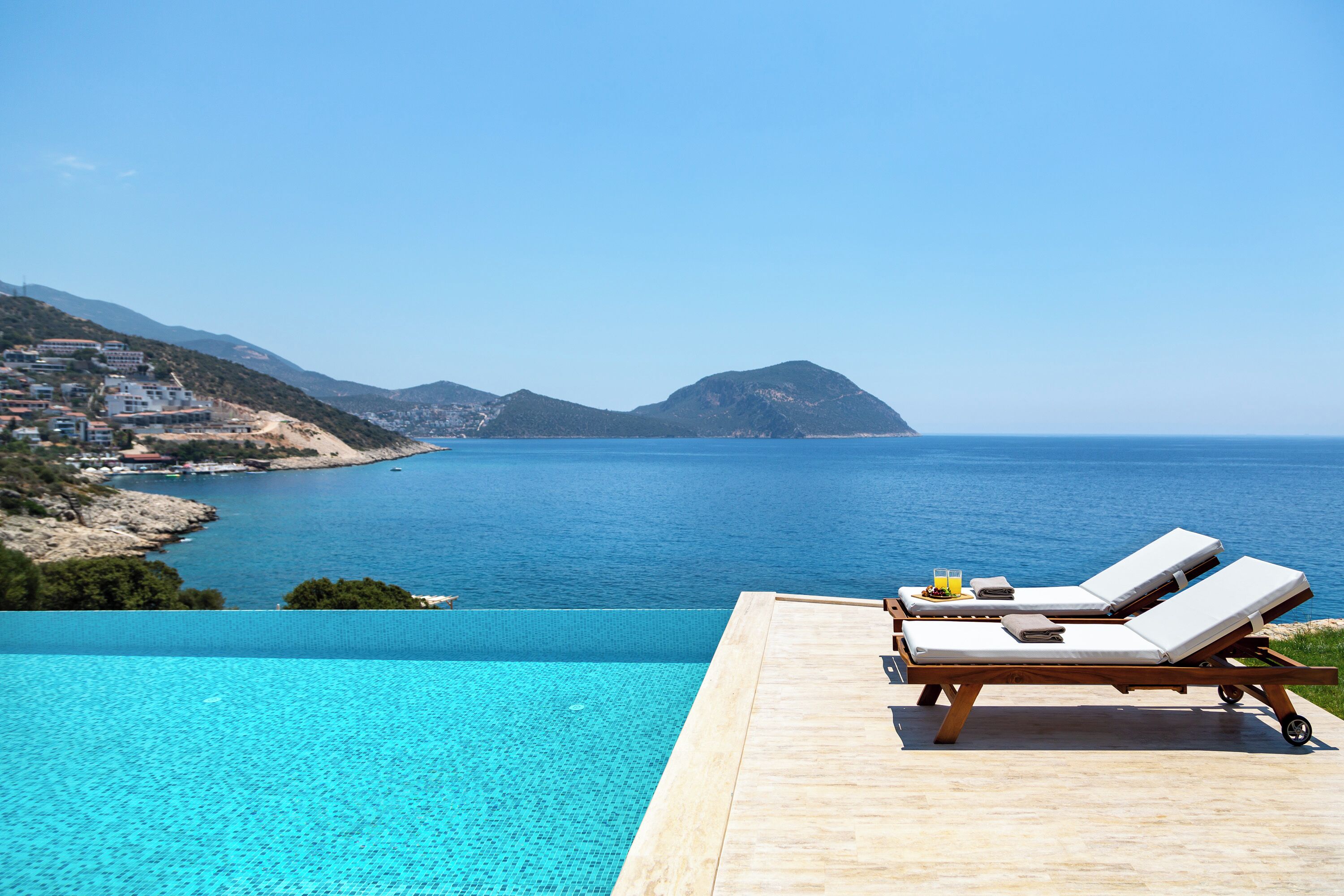 A poolside area with lounge chairs and a view of the sea.