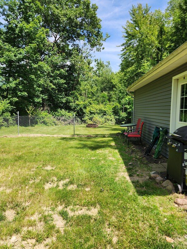 A backyard with a lawn, a grill, and a house. - Cardinal Cottage in Brooklyn, MI
(Brooklyn)