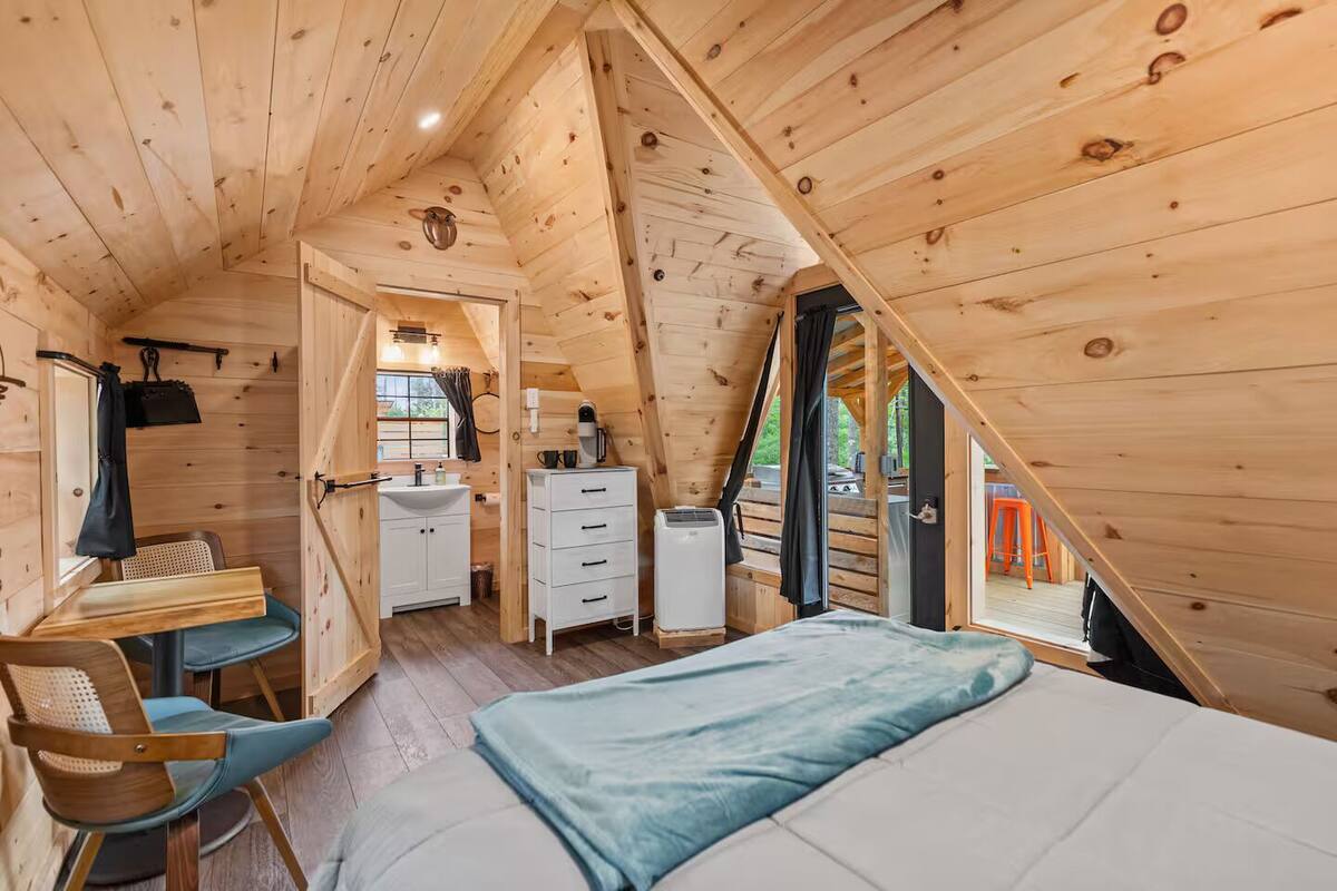 A cozy attic bedroom with a bed, a desk, and a small bathroom.