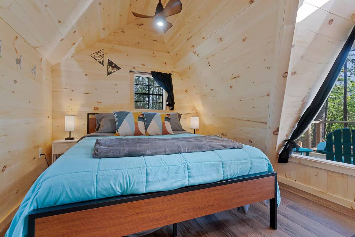 A wooden cabin bedroom with a bed, nightstands, and a window.