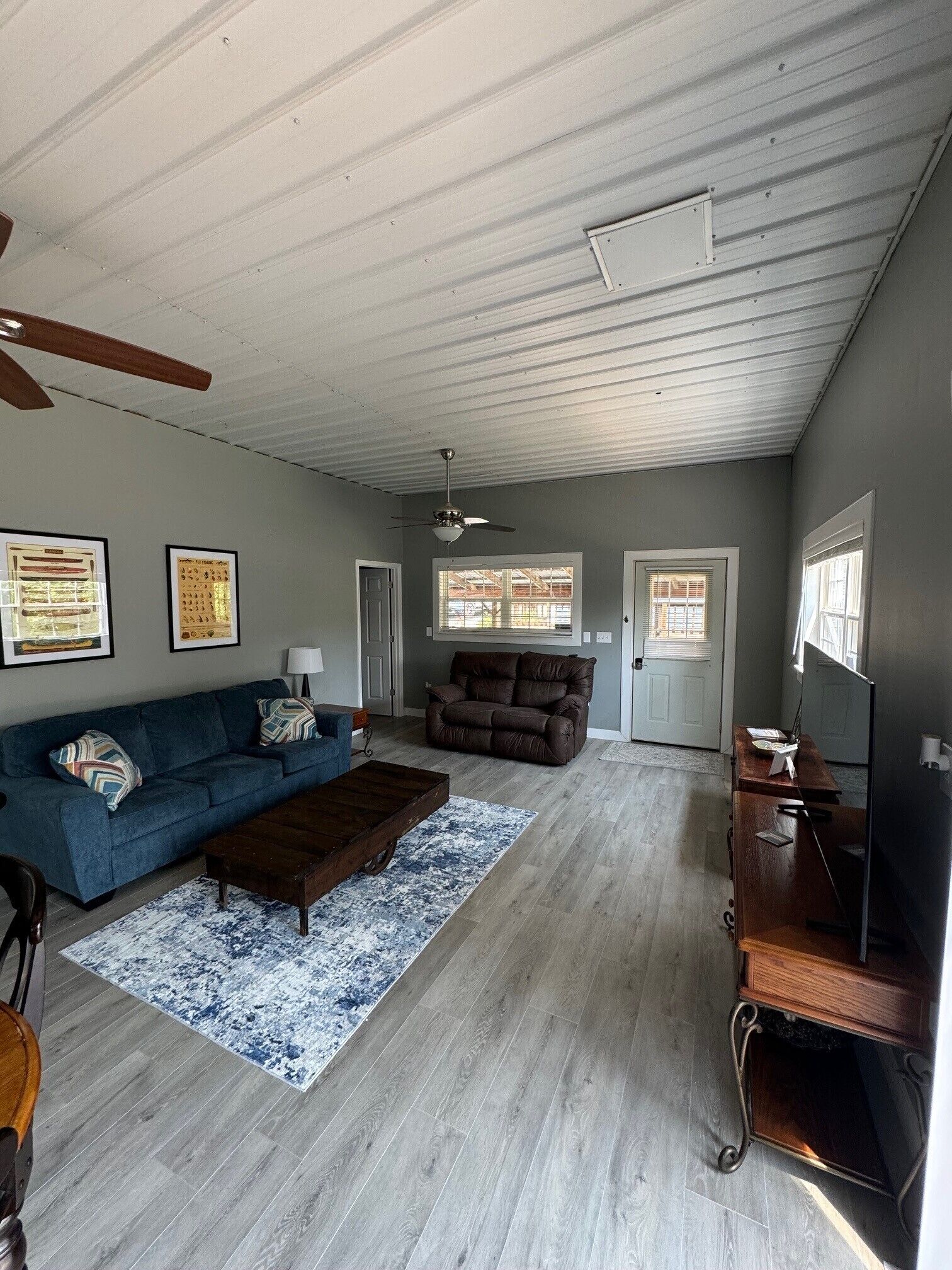 A spacious living room with a blue sofa, a brown leather couch, a wooden coffee table, and a TV stand.