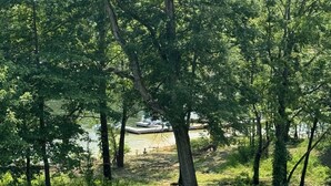 Une zone herbeuse avec des arbres et une jetée qui s’avance dans un plan d’eau.