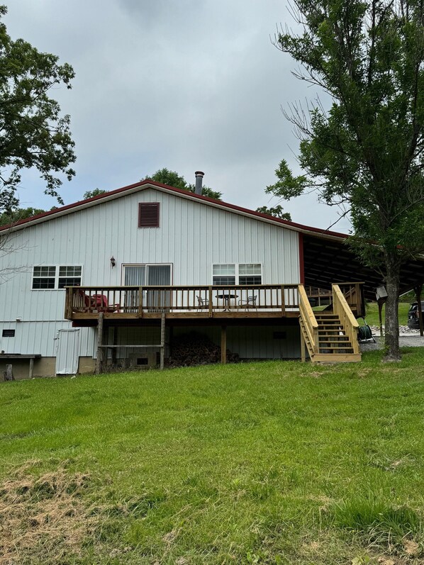 A white building with a wooden deck and a staircase leading to a covered area.