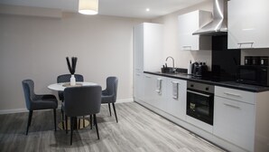 A modern kitchen with white cabinets, a black countertop, and a round dining table with chairs.